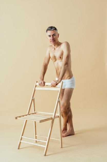 Uomo in posa per un set di bellezza positivo per il corpo in edizione maschile. Ragazzo senza camicia che indossa la biancheria intima dei pugili in studio