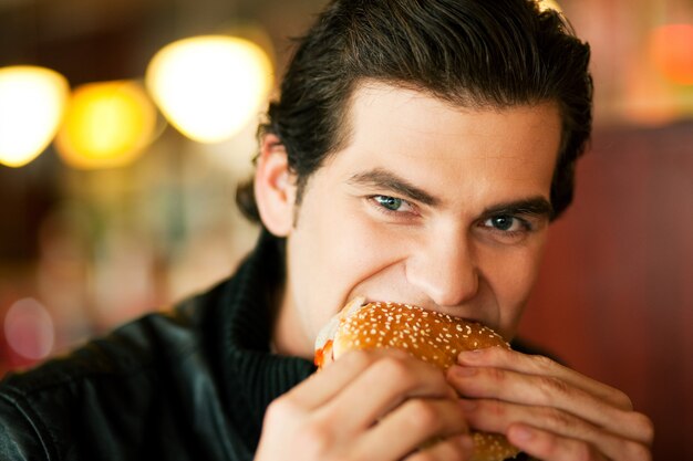 Uomo in ristorante che mangia hamburger