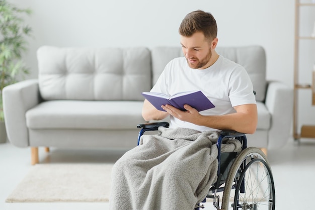 Uomo in sedia a rotelle che legge un libro a casa