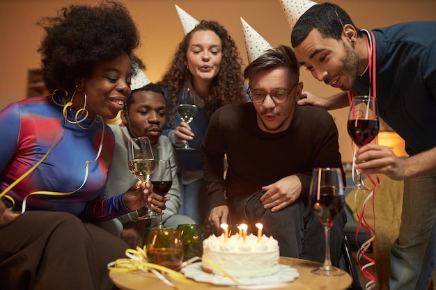 Uomo in sedia a rotelle che soffia candele sulla torta di compleanno