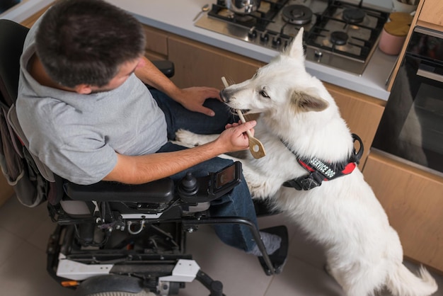 Uomo in sedia a rotelle e il suo cane da servizio in cucina