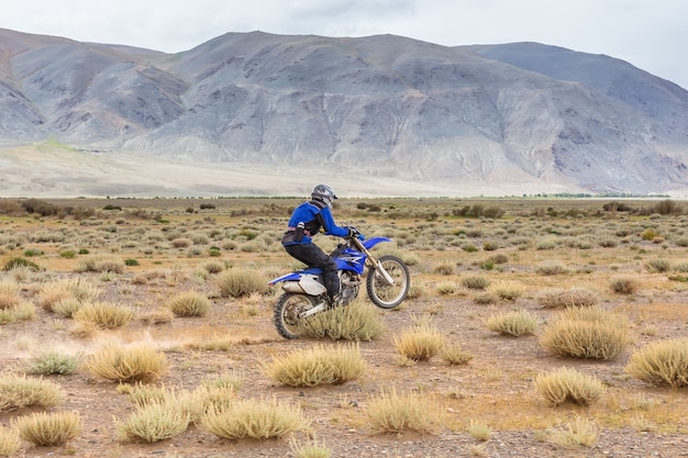 Uomo in sella a una moto da cross nelle steppe della Mongolia, sulle colline della Mongolia