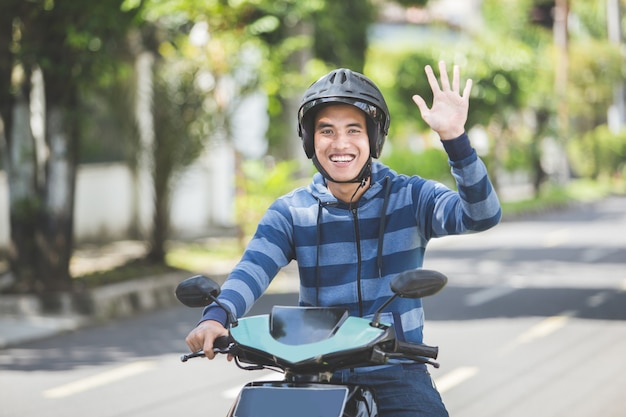 Uomo in sella a una moto e agitando la mano