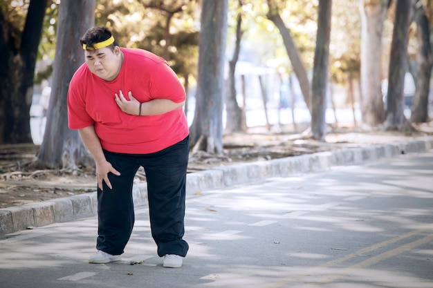 Uomo in sovrappeso che ha dolore al cuore dopo aver corso