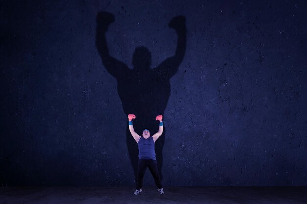 Uomo in sovrappeso con guantoni da boxe alzando le mani dopo l'esercizio