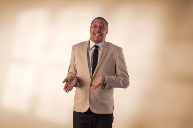 Uomo in tailleur beige in studio fotografico su uno sfondo con luci.