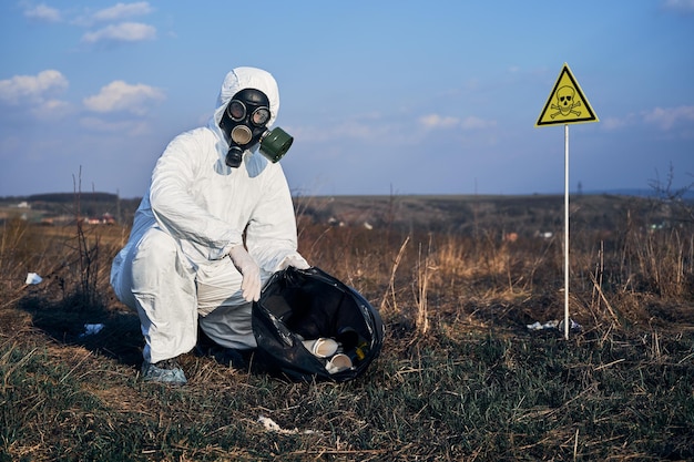 Uomo in tuta anti-radiazioni che raccoglie spazzatura per strada