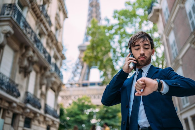 Uomo in tuta che usa il suo smartphone a Parigi Francia Operaio europeo Strada con vista sulla Torre Eiffel