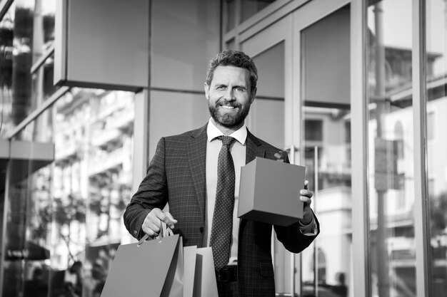 Uomo in tuta con borse della spesa miglior prezzo totale vendita uomo d'affari godendo shopping eccitato sorridente g