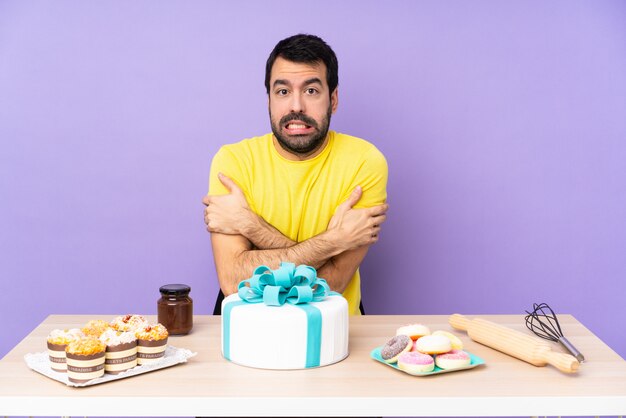 Uomo in un tavolo con un grande congelamento della torta