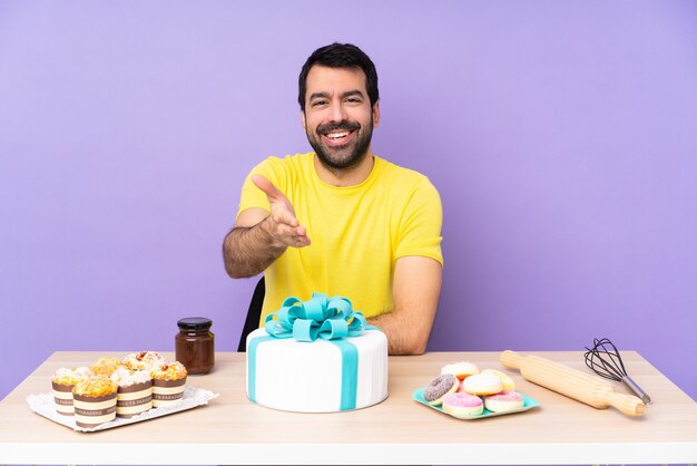 Uomo in un tavolo con una grande torta che stringe la mano per chiudere un buon affare