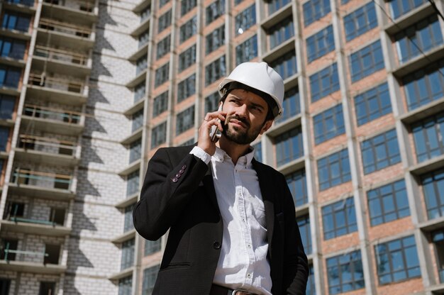 Uomo in un vestito e un casco protettivo parlando al telefono