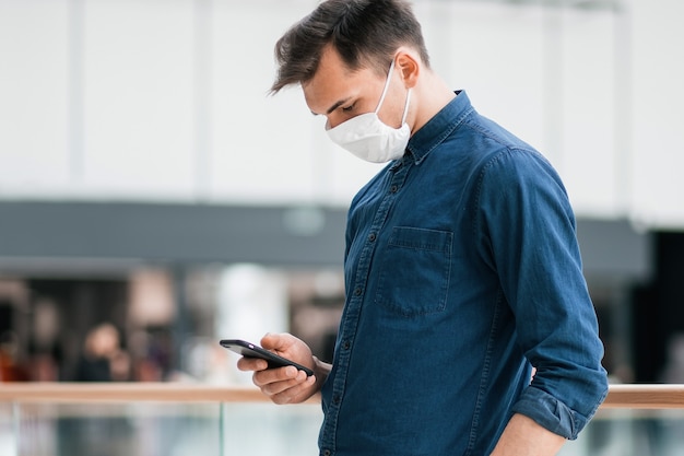 Uomo in una maschera protettiva che legge un messaggio di testo sul suo smartphone