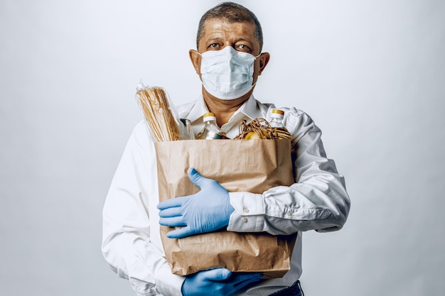 Uomo in una mascherina medica protettiva con una borsa da una drogheria