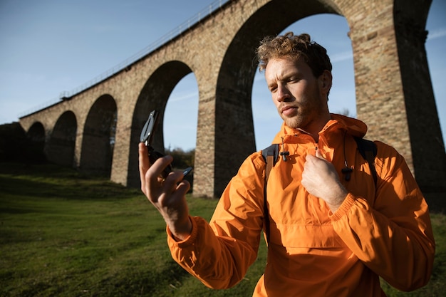 Uomo in viaggio su strada tenendo la bussola davanti all'acquedotto