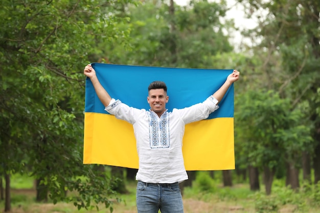 Uomo in vyshyvanka con bandiera dell'Ucraina all'aperto
