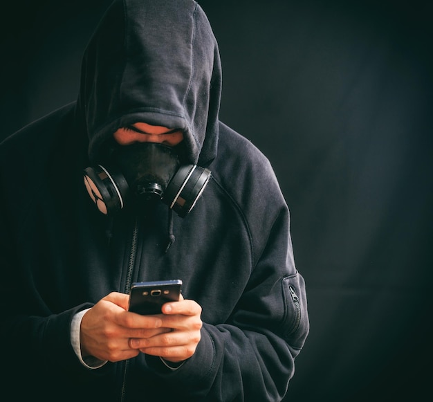 Uomo incappucciato che tiene uno smartphone