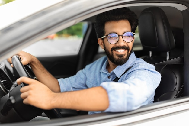 Uomo indiano allegro che guida un'auto sparato da vicino dall'esterno