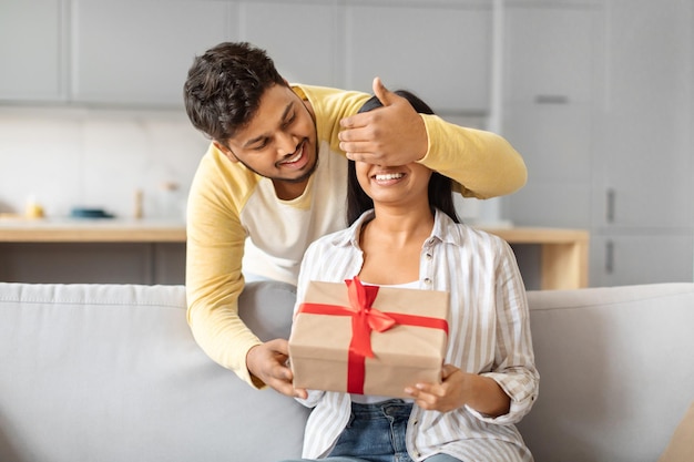 Uomo indiano che dà un regalo a una donna sul divano