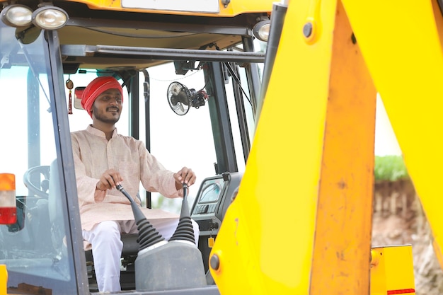 Uomo indiano che lavora con veicoli pesanti in cantiere.