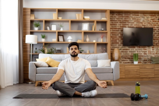 Uomo indiano che pratica la meditazione nella posa del loto a casa