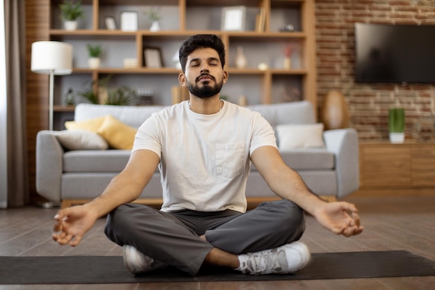 Uomo indiano che pratica la meditazione nella posa del loto a casa