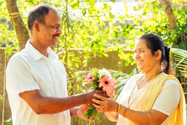 Uomo indiano che tiene il bouquet e fa una sorpresa per sua moglie all'aperto nel parco