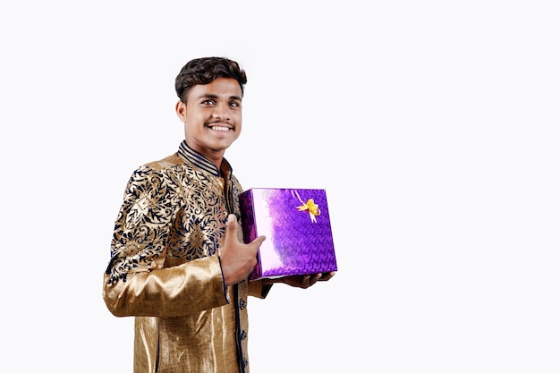 Uomo indiano che tiene scatole regalo a sorpresa e piatto vuoto su DIWALI o matrimoni o festival mentre indossa panni tradizionali in piedi isolati su sfondo bianco