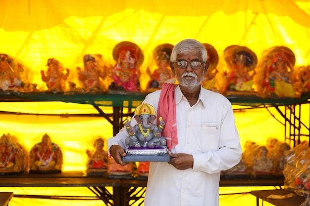 Uomo indiano che vende la scultura di ganesha