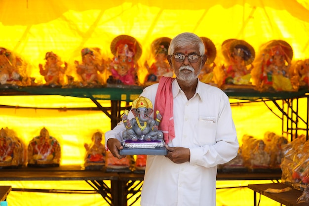 Uomo indiano che vende la scultura di ganesha