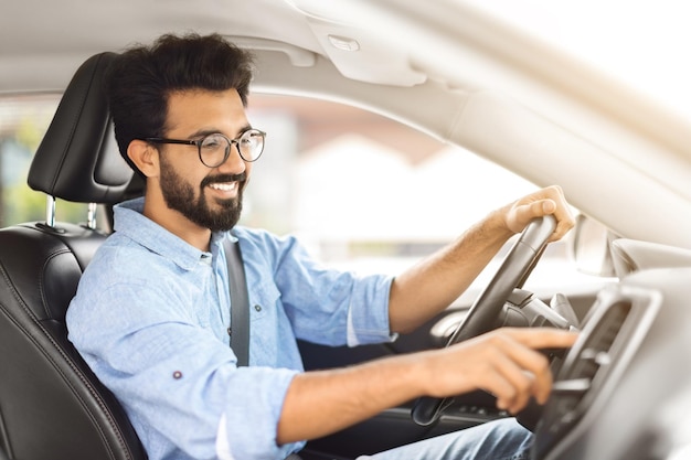 Uomo indiano felice che guida un'auto e ascolta musica