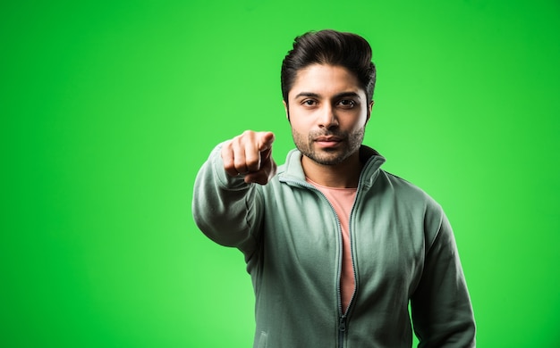 Uomo indiano soddisfatto che presenta, indica, mostra o fa pubblicità con le mani o le dita vuote. in piedi isolato