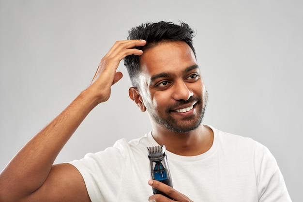 uomo indiano sorridente con un tagliacapelli che tocca i suoi capelli