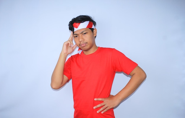 Uomo indonesiano che pensa e fa brainstorming per un'idea creativa con le mani sulla testa che indossa una maglietta rossa