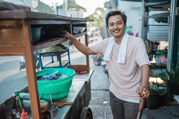 Uomo indonesiano in piedi dietro il suo tradizionale carrello alimentare