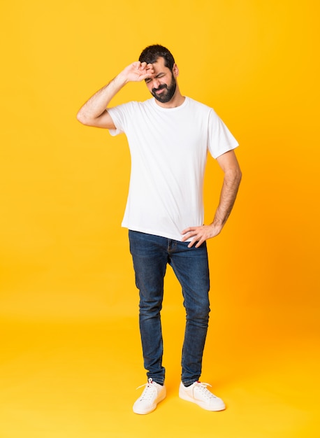 Uomo integrale con la barba sopra la parete gialla isolata con espressione stanca e malata