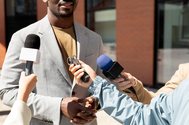 Uomo intervistato da giornalisti all'aperto