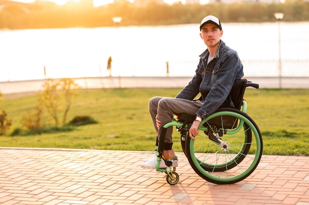 Uomo invalido seduto su una sedia a rotelle e godendo una passeggiata all'aperto foto di alta qualità