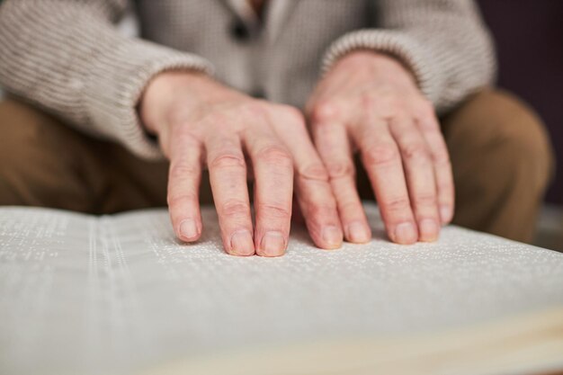 Uomo ipovedente che legge libro in Braille