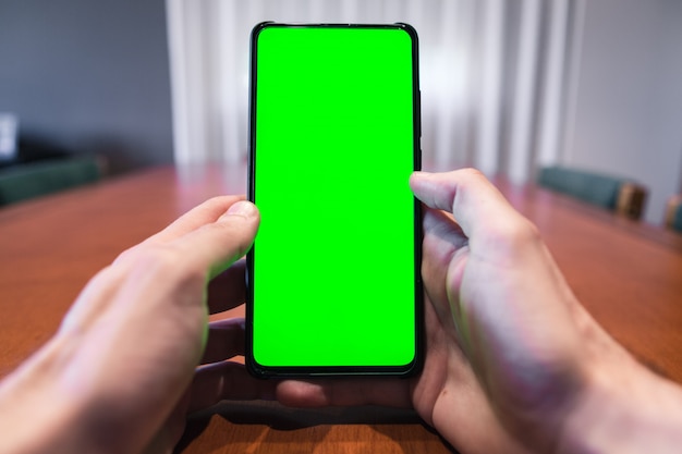 Uomo irriconoscibile che controlla il suo telefono con lo schermo verde a casa.