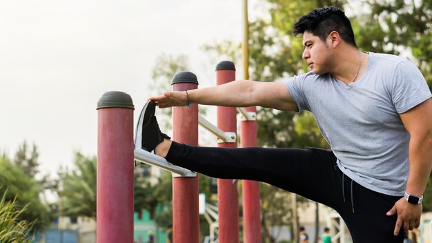 Uomo irriconoscibile che esegue allungamenti delle gambe in un parco pubblico in Messico.