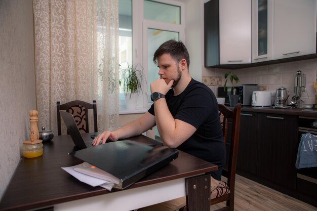 Uomo isolato che lavora alla cucina sul computer portatile