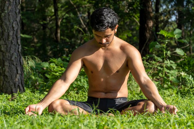 Uomo ispanico e latino che medita nel mezzo di una foresta che riceve i raggi del sole pelle marrone messico