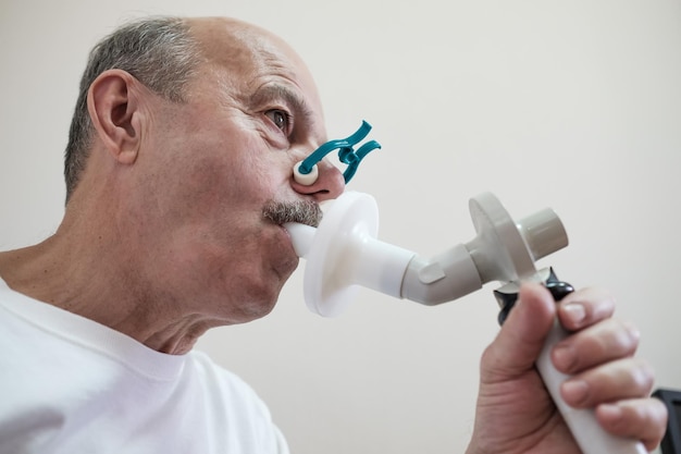 Uomo ispanico senior che testa la funzione respiratoria mediante spirometria