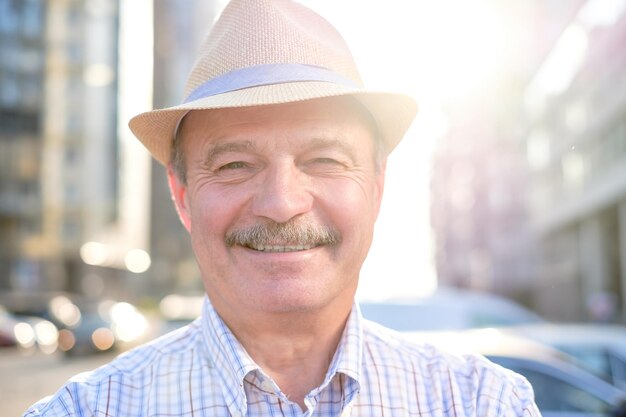 Uomo ispanico senior in pensione con cappello in piedi e sorridente