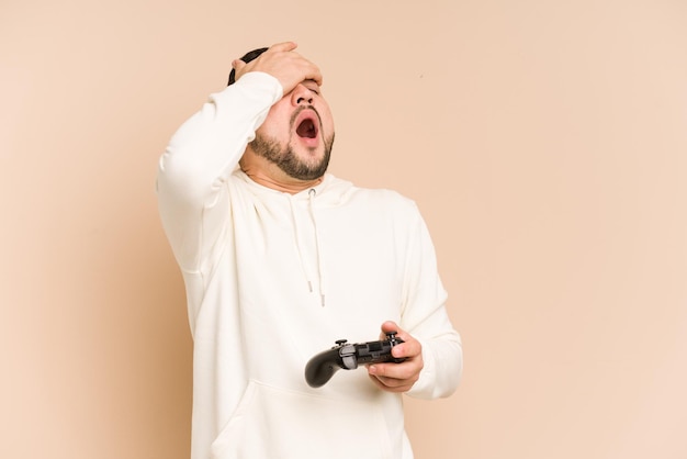 Uomo latino adulto che gioca con un controller di gioco isolato