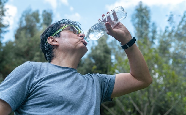 Uomo latino che beve acqua in una foresta