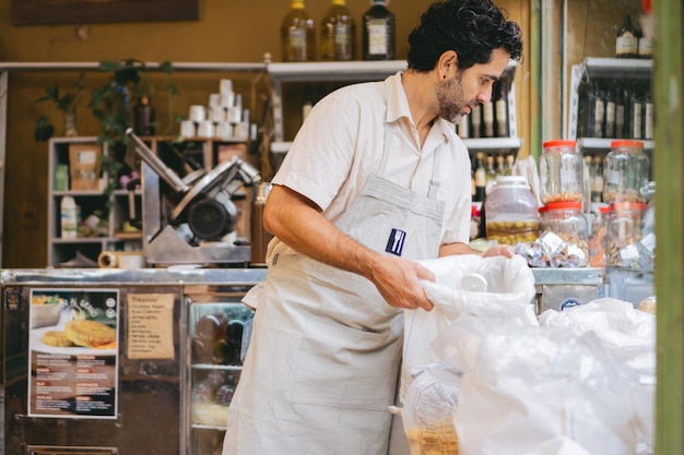 Uomo latino di mezza età che sistema alcuni sacchi al suo lavoro in una piccola impresa Copia spazio