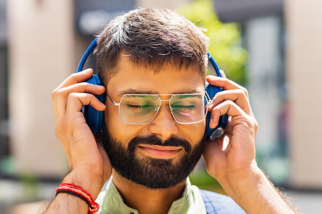 Uomo latino felice che ascolta le cuffie di musica alla città