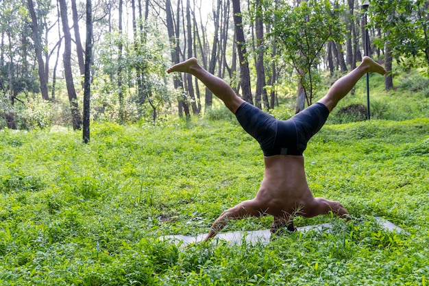 Uomo latinoamericano che fa yoga postura yoga postura Bee indietro Prsthatah Brahmara foresta